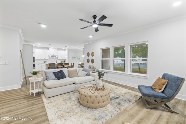 living room featuring light wood-type flooring, ceiling fan, and crown molding