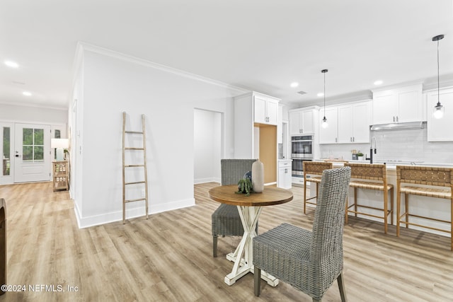 dining space with crown molding and light hardwood / wood-style floors