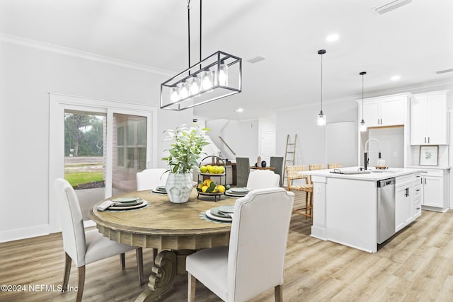 dining room with crown molding, light hardwood / wood-style flooring, and sink