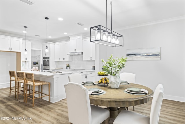 dining area with crown molding and light hardwood / wood-style flooring