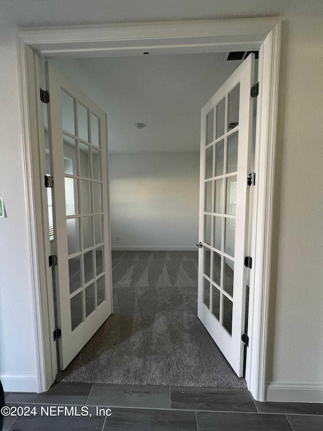 corridor with dark colored carpet and french doors