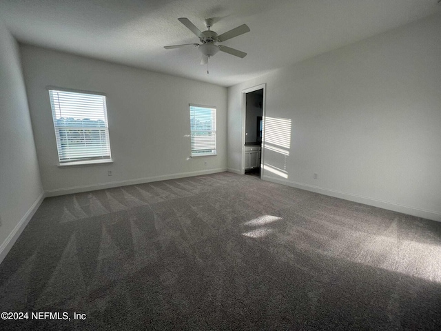 unfurnished room featuring dark carpet, plenty of natural light, and ceiling fan