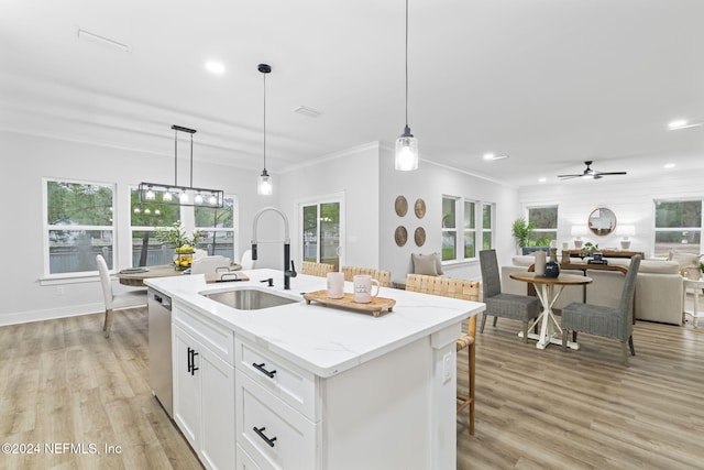 kitchen featuring a center island with sink, white cabinets, sink, stainless steel dishwasher, and light stone counters