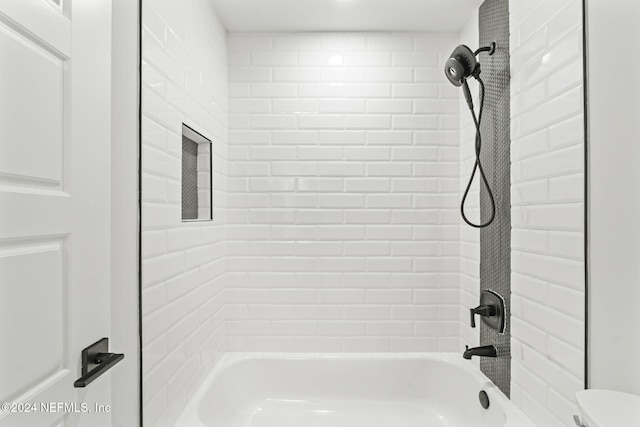 bathroom with tiled shower / bath combo and toilet