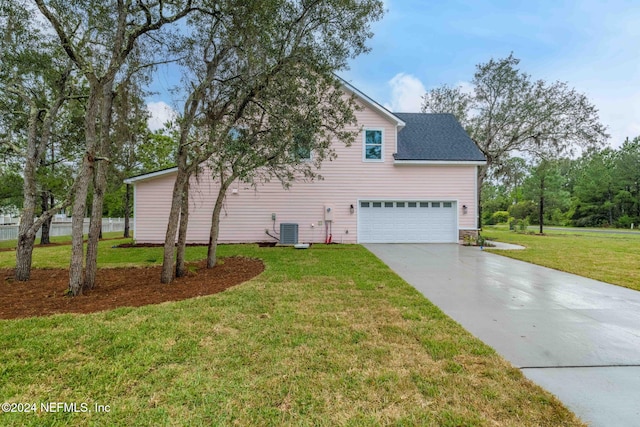 view of side of property with a garage, cooling unit, and a lawn