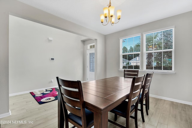 dining area with light hardwood / wood-style flooring and an inviting chandelier