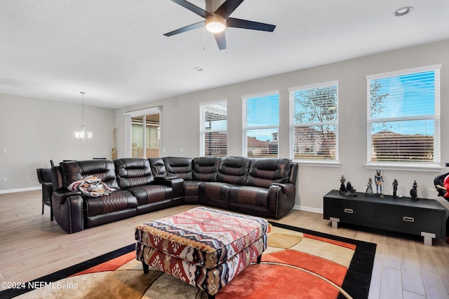 living room featuring ceiling fan with notable chandelier and light wood-type flooring