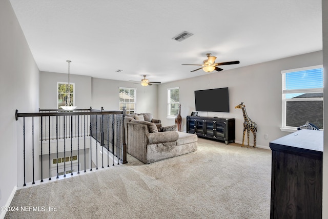 living room with a wealth of natural light, carpet, and ceiling fan with notable chandelier