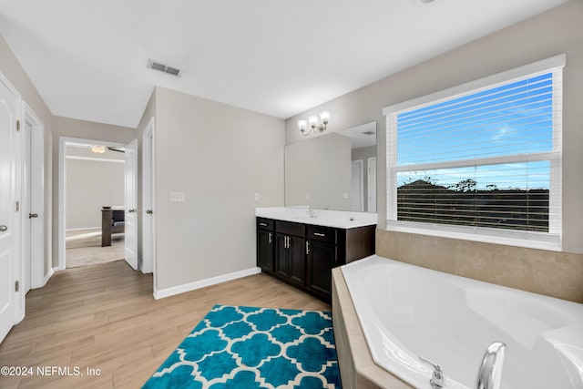 bathroom featuring wood-type flooring, vanity, and tiled tub