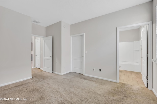 unfurnished bedroom with ensuite bathroom and light colored carpet