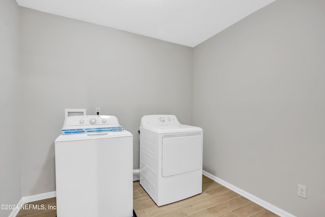 washroom with washer and clothes dryer and light wood-type flooring