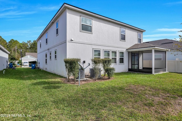 back of house with a sunroom, a lawn, and central AC