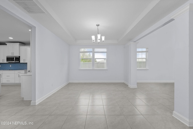 unfurnished dining area with a raised ceiling, light tile patterned floors, and an inviting chandelier