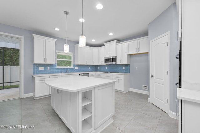 kitchen with white cabinets, decorative light fixtures, a kitchen island, and plenty of natural light