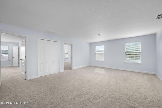 unfurnished bedroom featuring light carpet and a textured ceiling