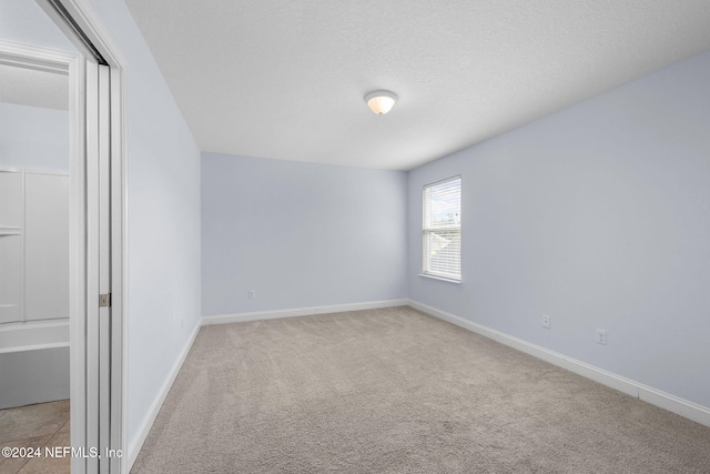 unfurnished room featuring light colored carpet and a textured ceiling