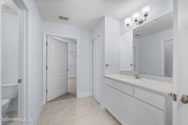 bathroom with tile patterned flooring, vanity, a textured ceiling, and toilet