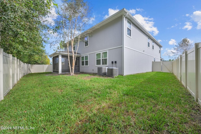 back of property featuring central AC unit and a lawn