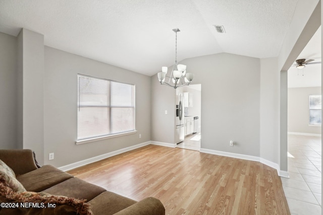 living room with a textured ceiling, ceiling fan with notable chandelier, light hardwood / wood-style floors, and vaulted ceiling