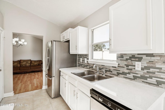 kitchen with an inviting chandelier, sink, vaulted ceiling, light tile patterned floors, and white cabinetry