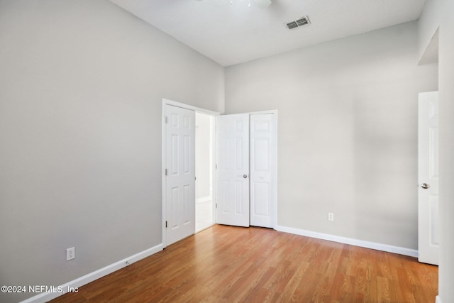 unfurnished bedroom with a towering ceiling and light wood-type flooring