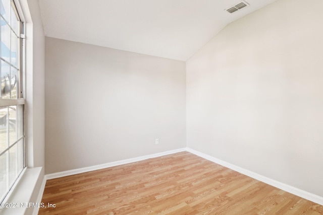 spare room featuring a wealth of natural light, lofted ceiling, and light wood-type flooring