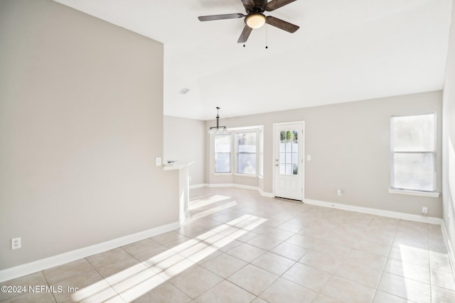 spare room featuring light tile patterned floors and ceiling fan with notable chandelier