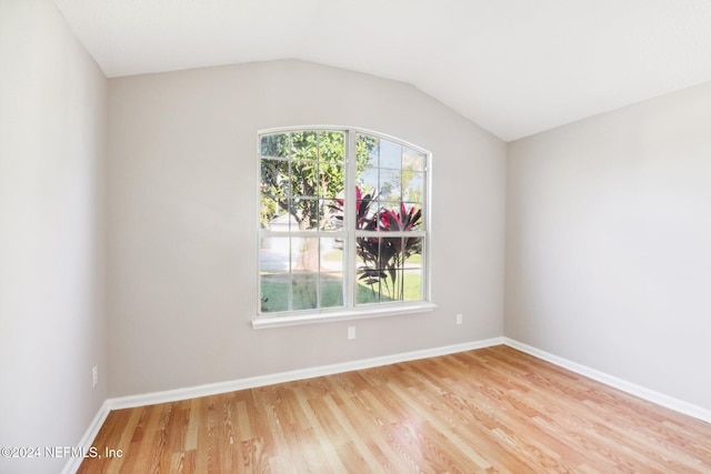 empty room featuring light wood-type flooring and vaulted ceiling