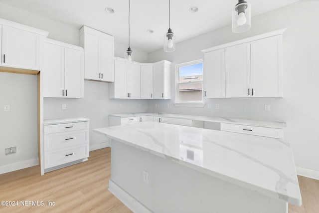 kitchen featuring light stone countertops, a center island, decorative light fixtures, and white cabinetry