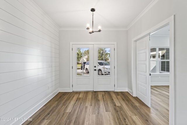 entryway with an inviting chandelier, french doors, crown molding, wooden walls, and wood-type flooring