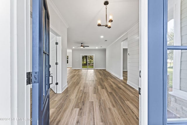 foyer entrance with hardwood / wood-style floors, ceiling fan with notable chandelier, and ornamental molding