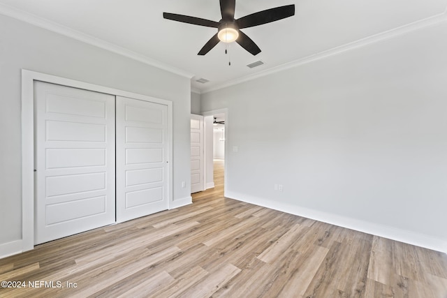 unfurnished bedroom with a closet, light hardwood / wood-style flooring, ceiling fan, and crown molding