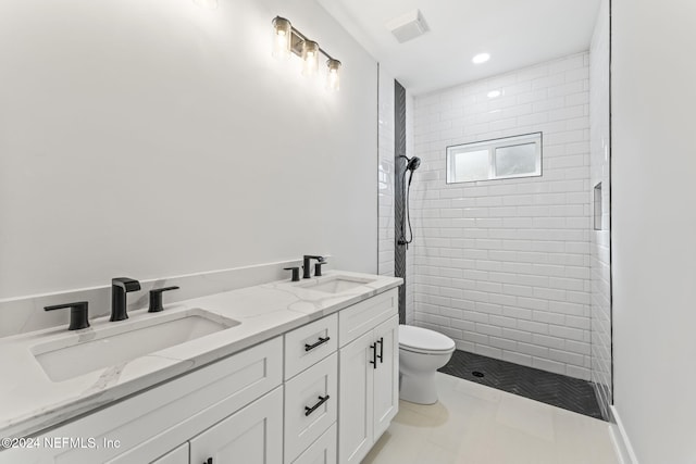 bathroom with tile patterned flooring, vanity, toilet, and tiled shower