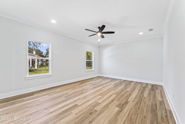 spare room featuring light wood-type flooring, ornamental molding, and a wealth of natural light