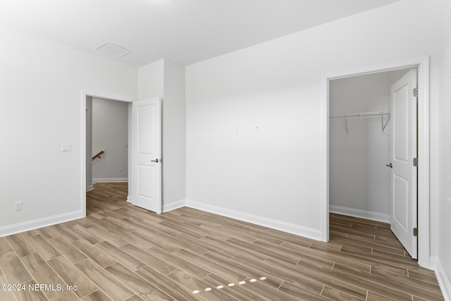 unfurnished bedroom with light hardwood / wood-style floors, a spacious closet, and a closet