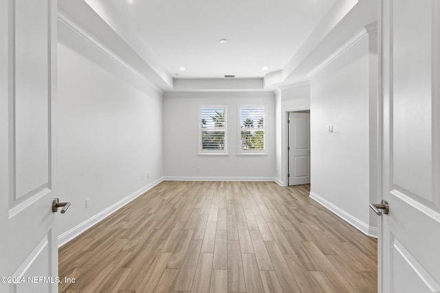 unfurnished room featuring a tray ceiling and light wood-type flooring