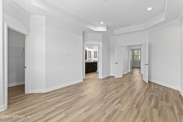 interior space featuring a walk in closet, light hardwood / wood-style flooring, and ensuite bath