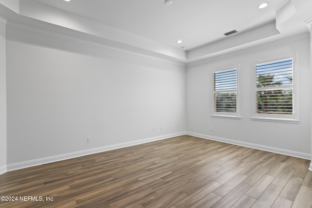 spare room featuring hardwood / wood-style flooring, a raised ceiling, and ornamental molding