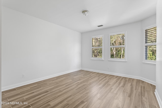 empty room with plenty of natural light and light hardwood / wood-style flooring