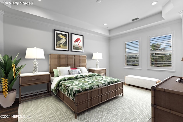 bedroom featuring a tray ceiling, crown molding, and hardwood / wood-style flooring