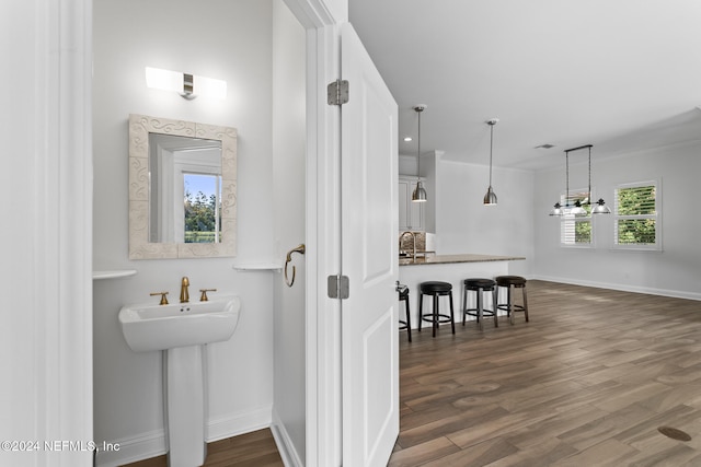 bathroom with hardwood / wood-style flooring, sink, crown molding, and an inviting chandelier