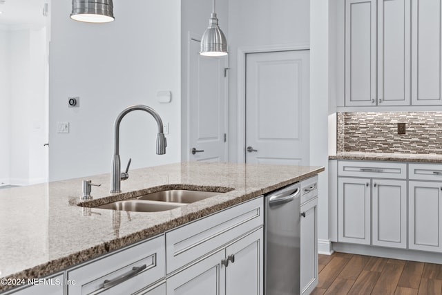 kitchen featuring light stone countertops, sink, decorative light fixtures, dishwasher, and dark hardwood / wood-style floors