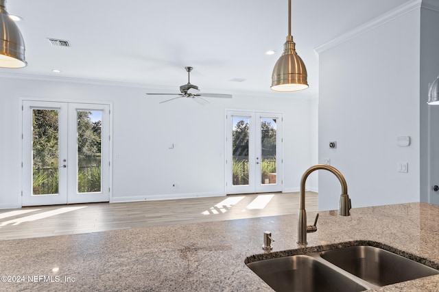 kitchen with french doors, sink, hardwood / wood-style flooring, ornamental molding, and decorative light fixtures