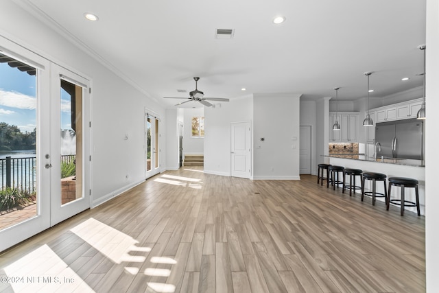 unfurnished living room with ceiling fan, french doors, crown molding, and light hardwood / wood-style flooring