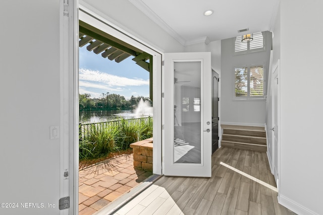 entryway with plenty of natural light, light hardwood / wood-style floors, a water view, and ornamental molding