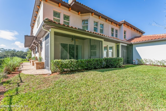 rear view of property featuring ceiling fan and a lawn