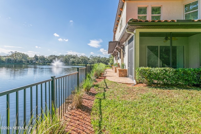 view of yard featuring ceiling fan and a water view