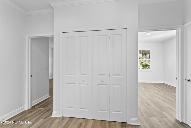 unfurnished bedroom featuring a closet, ornamental molding, and light hardwood / wood-style flooring