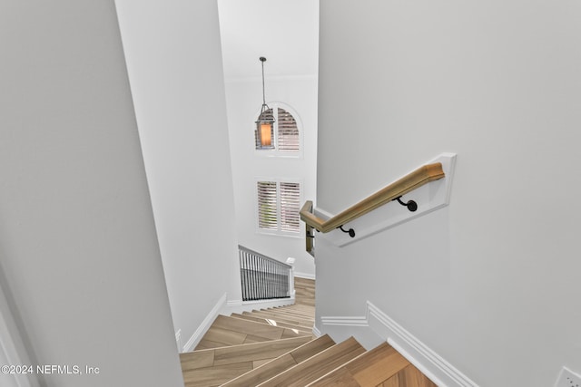 stairway with crown molding and wood-type flooring