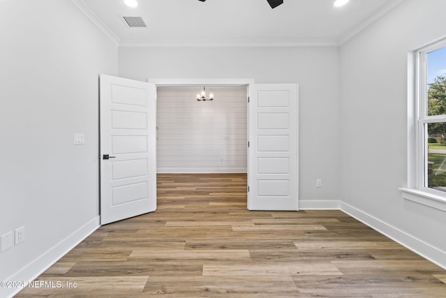 unfurnished room with hardwood / wood-style flooring, ornamental molding, and ceiling fan with notable chandelier